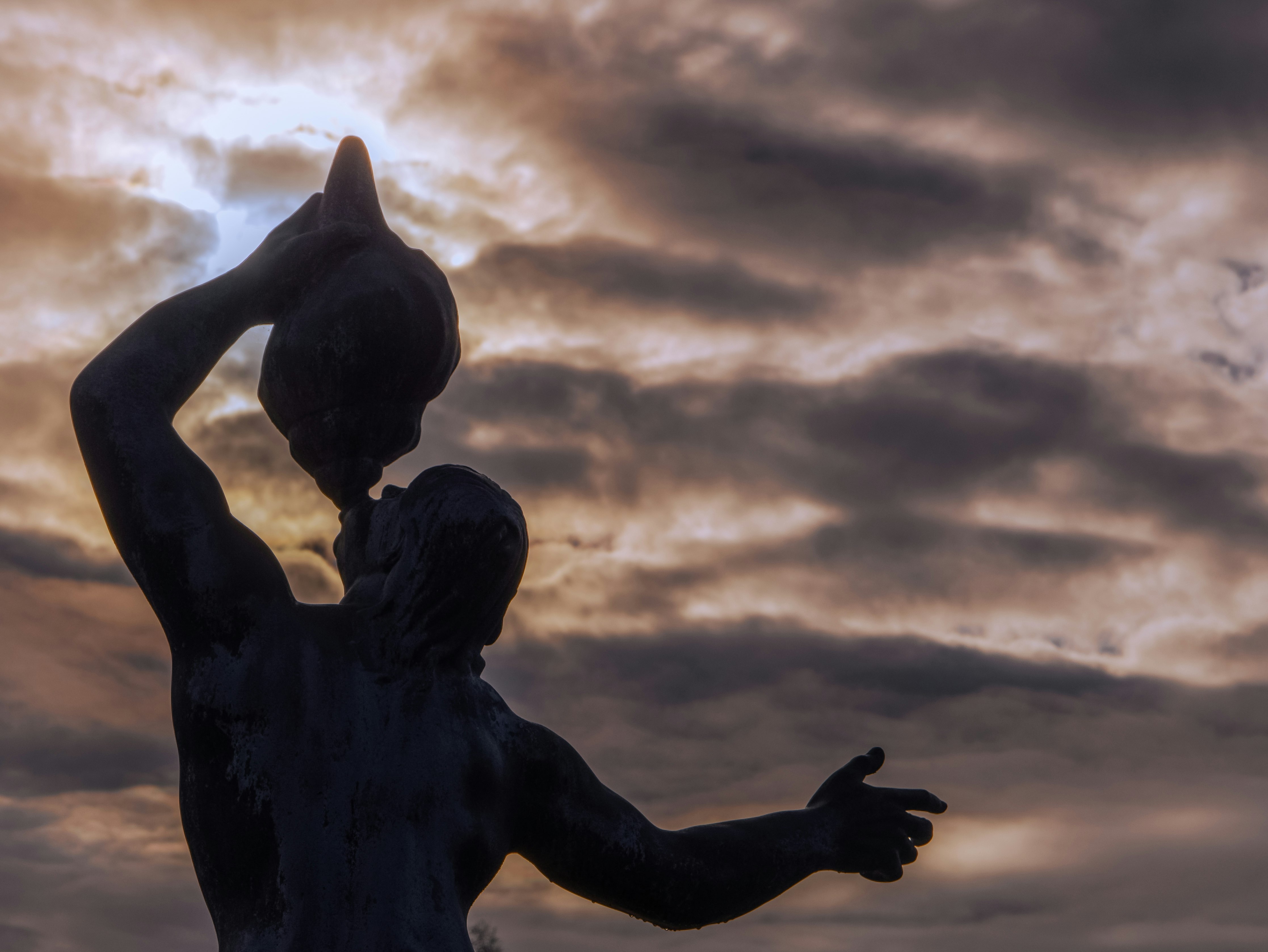 silhouette of man statue under cloudy sky during daytime